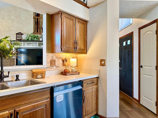 kitchen featuring dark wood finished floors, light countertops, brown cabinetry, a sink, and dishwashing machine