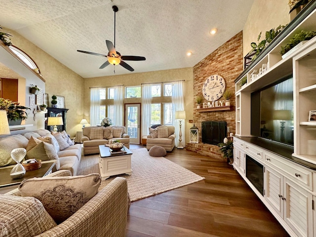 living room with dark wood-type flooring, a brick fireplace, ceiling fan, and a textured ceiling