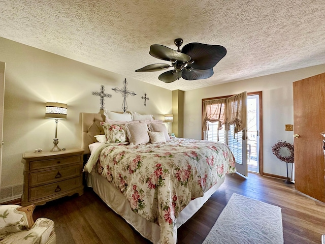 bedroom featuring access to exterior, dark wood-type flooring, a ceiling fan, a textured ceiling, and baseboards