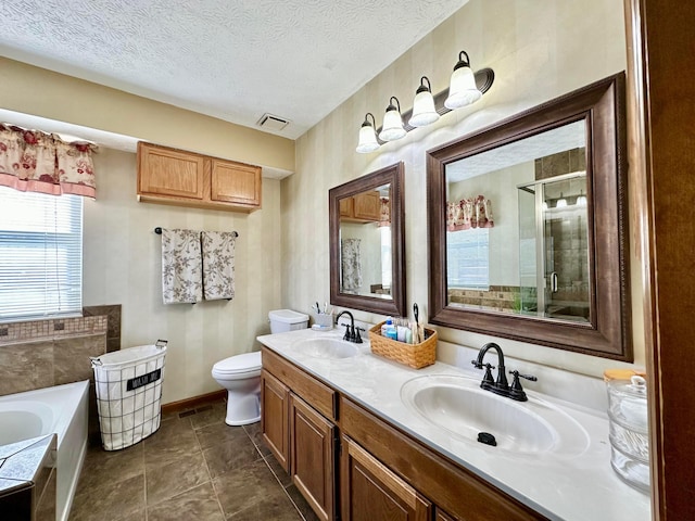 bathroom featuring a textured ceiling, a stall shower, a sink, and a bath