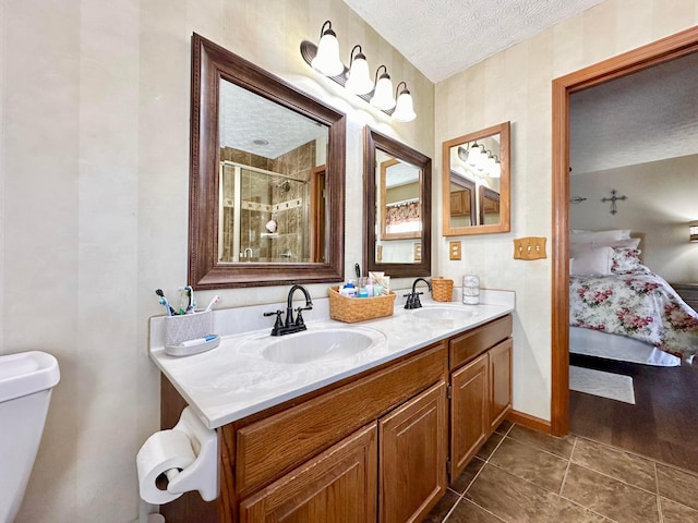 ensuite bathroom featuring connected bathroom, a sink, a shower stall, and a textured ceiling