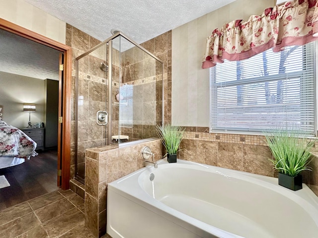 ensuite bathroom featuring a textured ceiling, ensuite bathroom, tile patterned flooring, a garden tub, and a stall shower