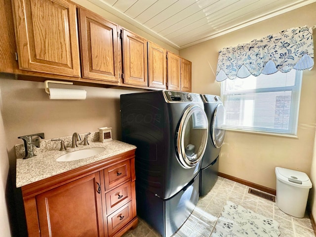 washroom featuring cabinet space, visible vents, a sink, separate washer and dryer, and baseboards