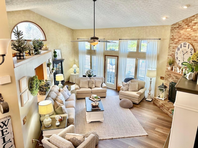 living area with plenty of natural light, high vaulted ceiling, a fireplace, and wood-type flooring