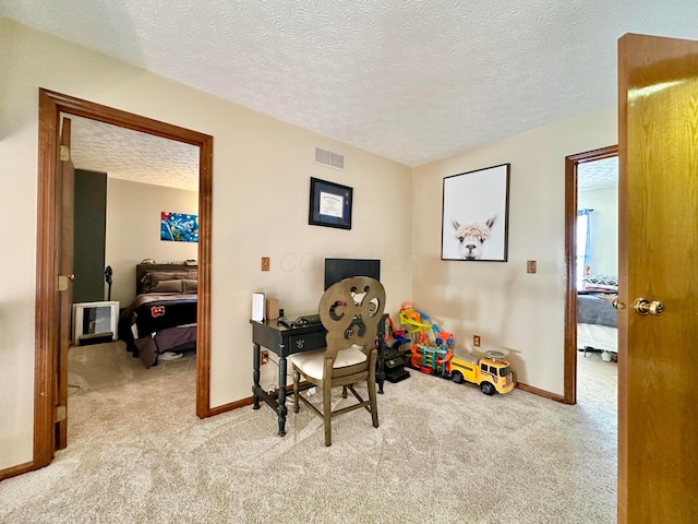 carpeted office with visible vents, a textured ceiling, and baseboards