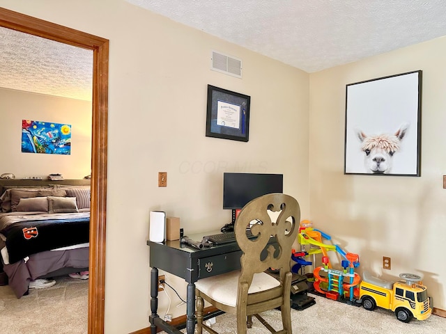 office area featuring a textured ceiling, visible vents, and carpet flooring