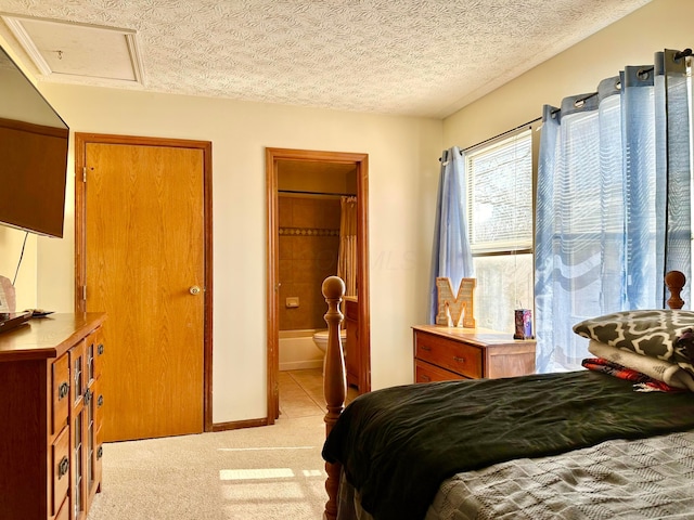 bedroom featuring attic access, light colored carpet, a textured ceiling, and baseboards