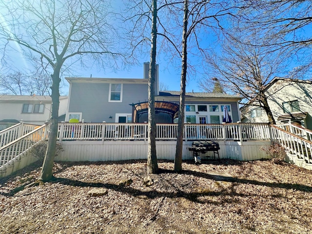 back of property featuring a chimney, stairway, and a wooden deck