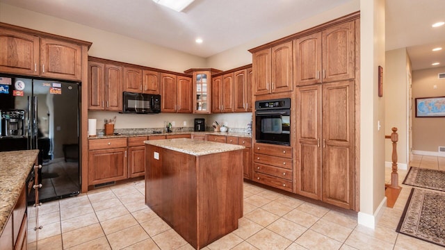 kitchen featuring a kitchen island, glass insert cabinets, light tile patterned floors, brown cabinets, and black appliances