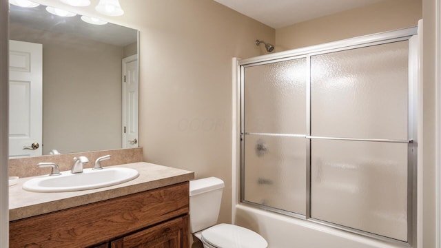 bathroom featuring vanity, toilet, and shower / bath combination with glass door