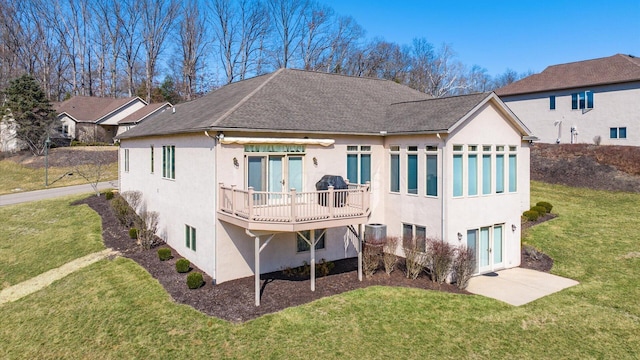 rear view of property with stucco siding, french doors, a lawn, and a deck