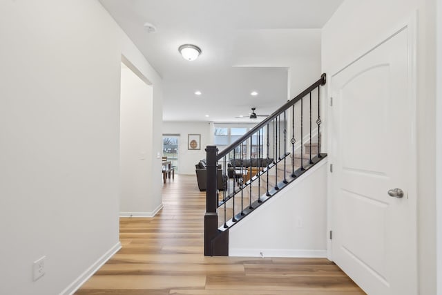 stairway featuring recessed lighting, wood finished floors, and baseboards