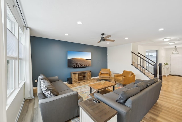 living room featuring light wood-type flooring, baseboards, recessed lighting, and stairs