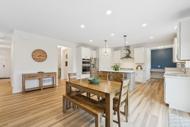 dining space featuring baseboards, light wood-type flooring, and recessed lighting