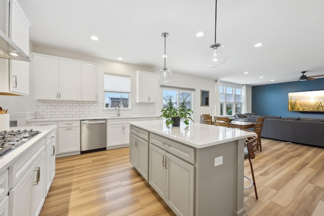 kitchen featuring a healthy amount of sunlight, light wood finished floors, a kitchen bar, and appliances with stainless steel finishes