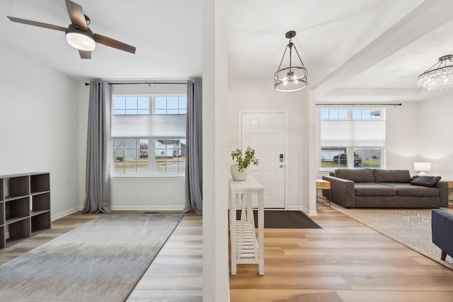 foyer entrance with ceiling fan with notable chandelier, wood finished floors, and baseboards