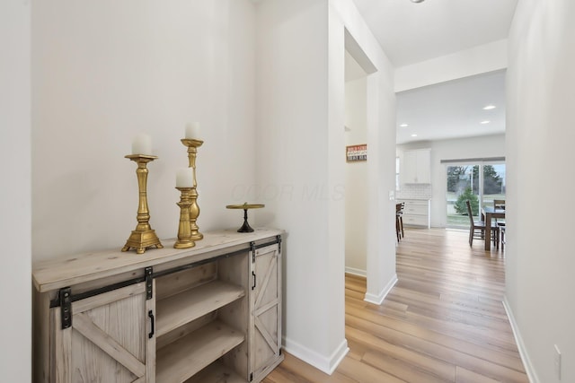 corridor featuring light wood finished floors, recessed lighting, and baseboards