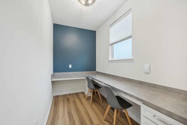 office space with built in study area, light wood-style flooring, and baseboards