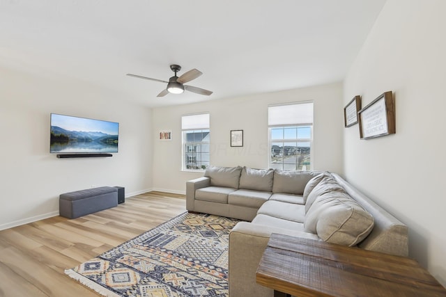 living room with a ceiling fan, light wood-style flooring, and baseboards