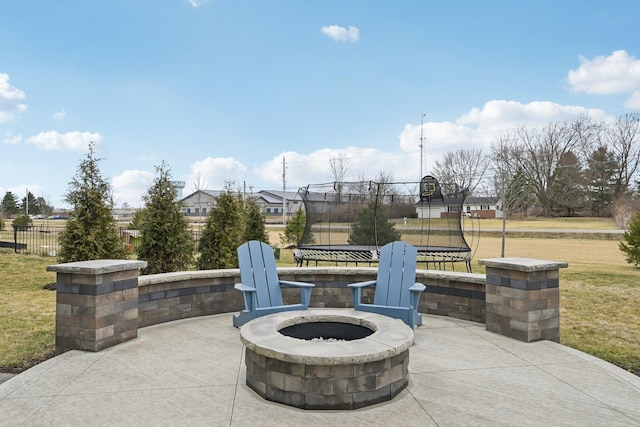 view of patio / terrace with an outdoor fire pit, a trampoline, and fence