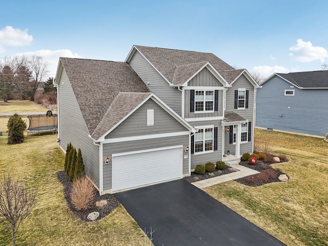 traditional home with a shingled roof, aphalt driveway, a trampoline, board and batten siding, and a front yard