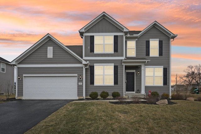 traditional-style house featuring a garage, board and batten siding, a front lawn, and aphalt driveway