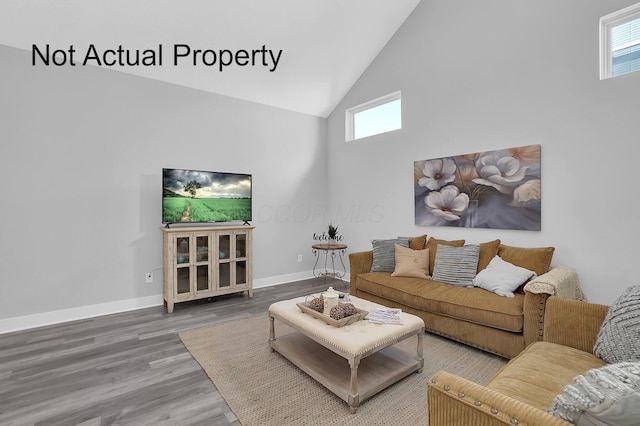 living area with high vaulted ceiling, a wealth of natural light, baseboards, and wood finished floors