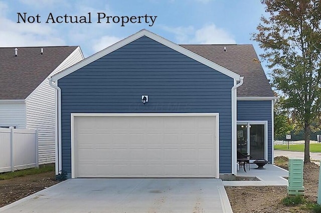 garage with concrete driveway and fence