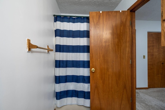 full bath featuring a textured ceiling, a shower with shower curtain, and baseboards