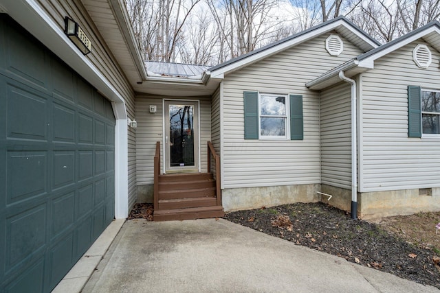 entrance to property featuring a garage, metal roof, crawl space, and concrete driveway