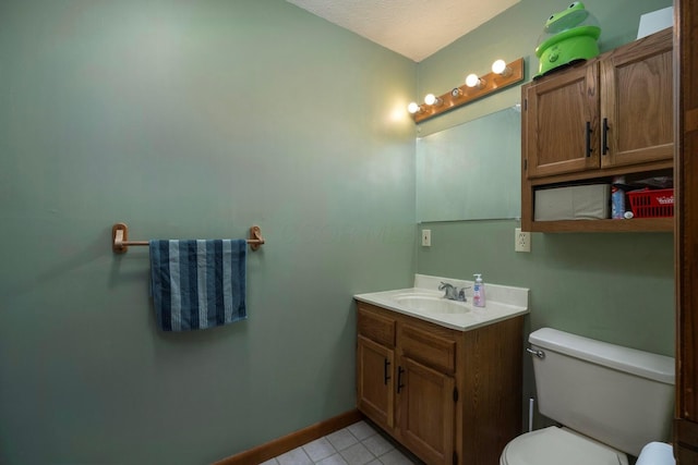 bathroom with tile patterned flooring, baseboards, vanity, and toilet