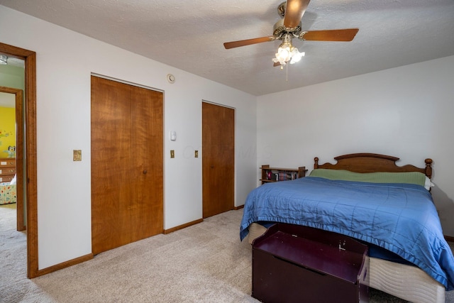 bedroom with ceiling fan, baseboards, a textured ceiling, and light colored carpet