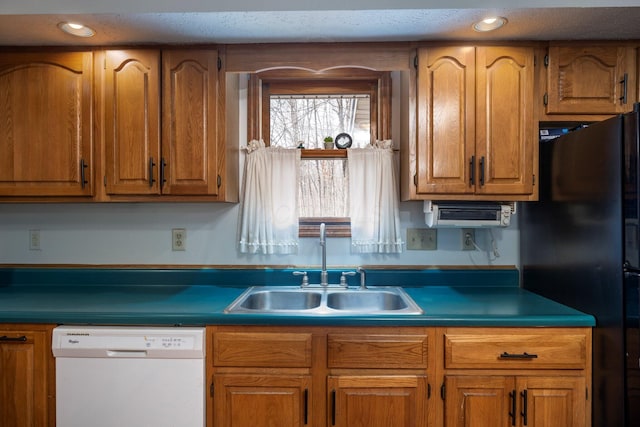 kitchen with white dishwasher, brown cabinets, a sink, and freestanding refrigerator