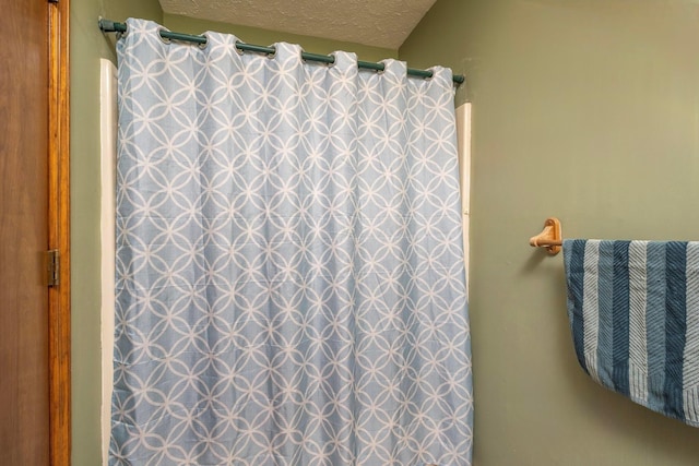 full bathroom with curtained shower and a textured ceiling