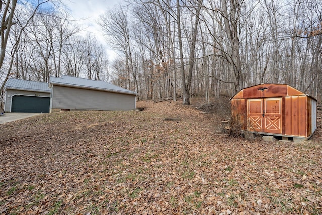 view of yard with a garage, concrete driveway, and an outbuilding