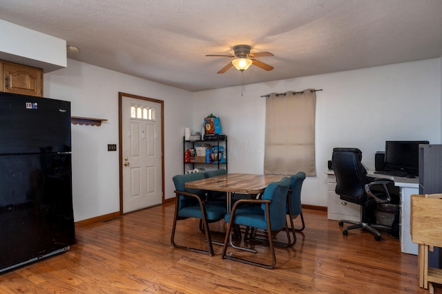 dining space with light wood finished floors, ceiling fan, baseboards, and a textured ceiling