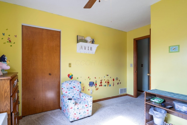 sitting room with ceiling fan, carpet flooring, visible vents, and baseboards