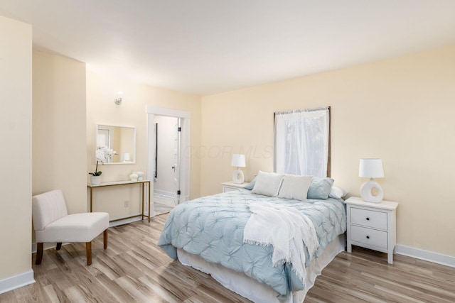 bedroom featuring light wood finished floors and baseboards