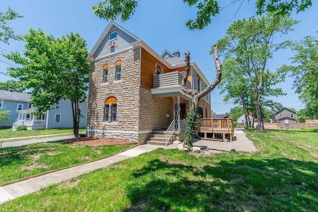 view of front facade with a chimney, stone siding, a balcony, and a front lawn