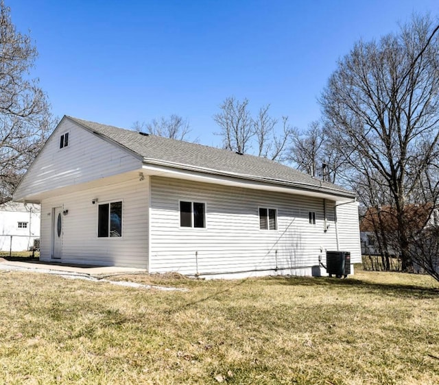 view of home's exterior with central AC unit, a lawn, and roof with shingles