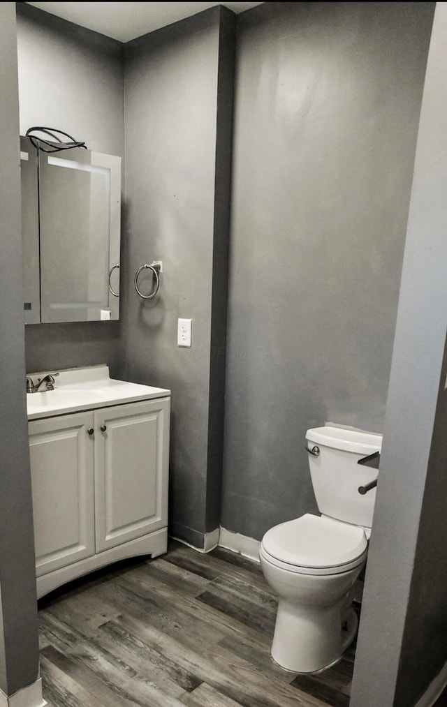 bathroom with baseboards, toilet, wood finished floors, and vanity