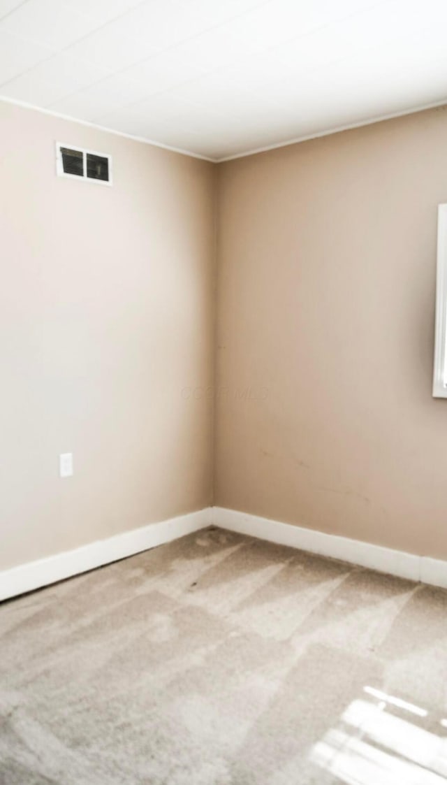 carpeted empty room featuring baseboards and visible vents