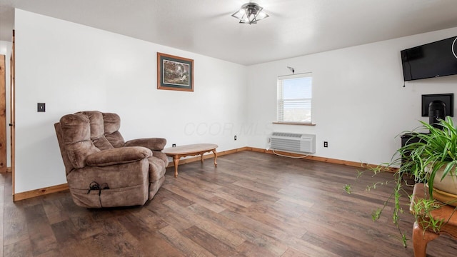 sitting room featuring an AC wall unit, baseboards, and wood finished floors