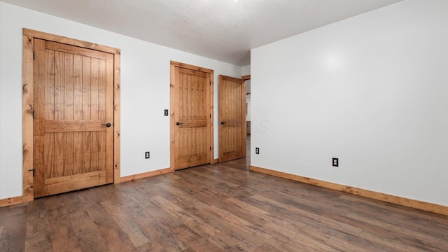 unfurnished bedroom with a textured ceiling, baseboards, and wood finished floors