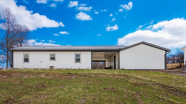 rear view of property with an attached carport, metal roof, and a lawn