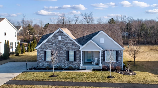 traditional-style house with a porch, a front lawn, and a shingled roof