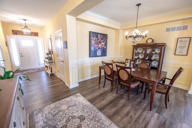 dining room with visible vents, a wainscoted wall, ornamental molding, dark wood-style floors, and an inviting chandelier