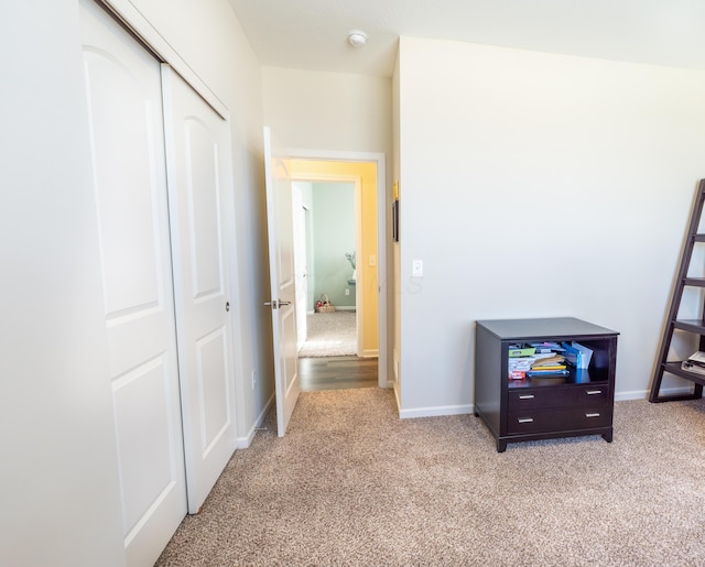 hallway featuring light carpet and baseboards