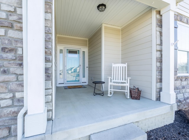 doorway to property with stone siding and a porch