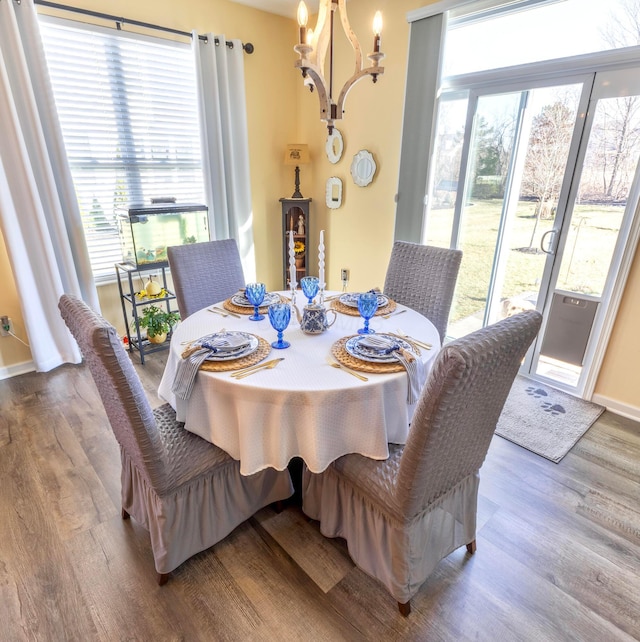 dining space with a chandelier, baseboards, a healthy amount of sunlight, and wood finished floors